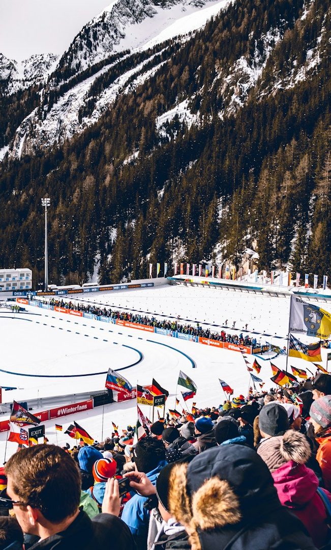 Menschenmenge beobachtet ein Wintersportereignis in schneebedeckter Umgebung.